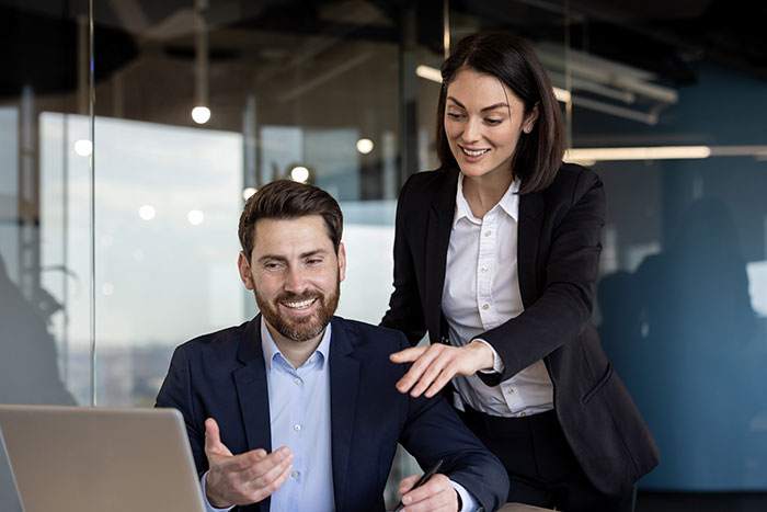 man and woman looking at work computer in office
