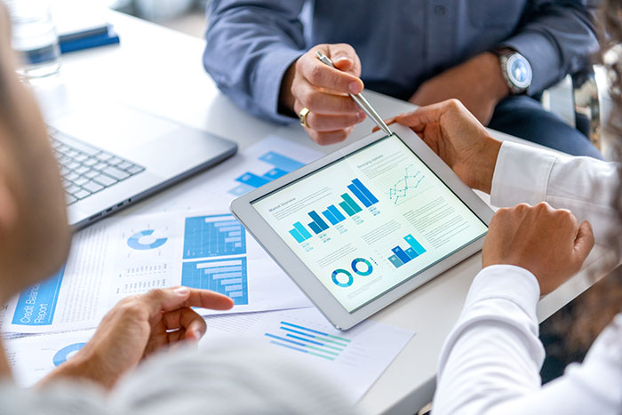 view of hands holding tablet and business charts on table