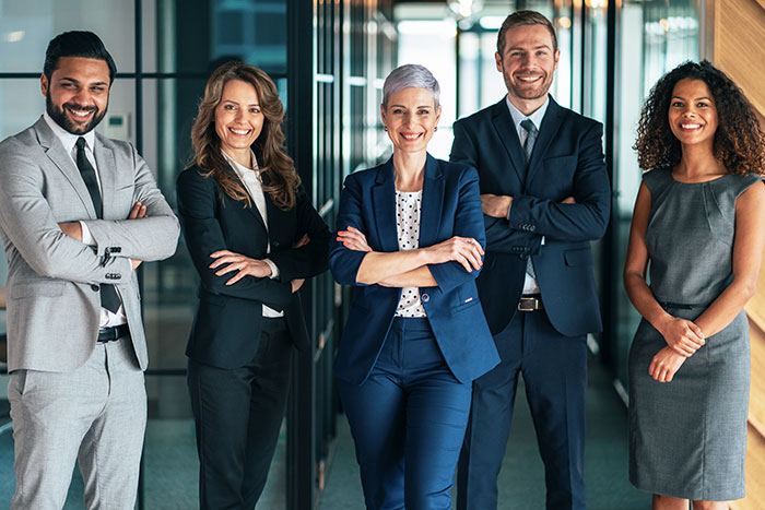 group of men and women standing and smiling in office